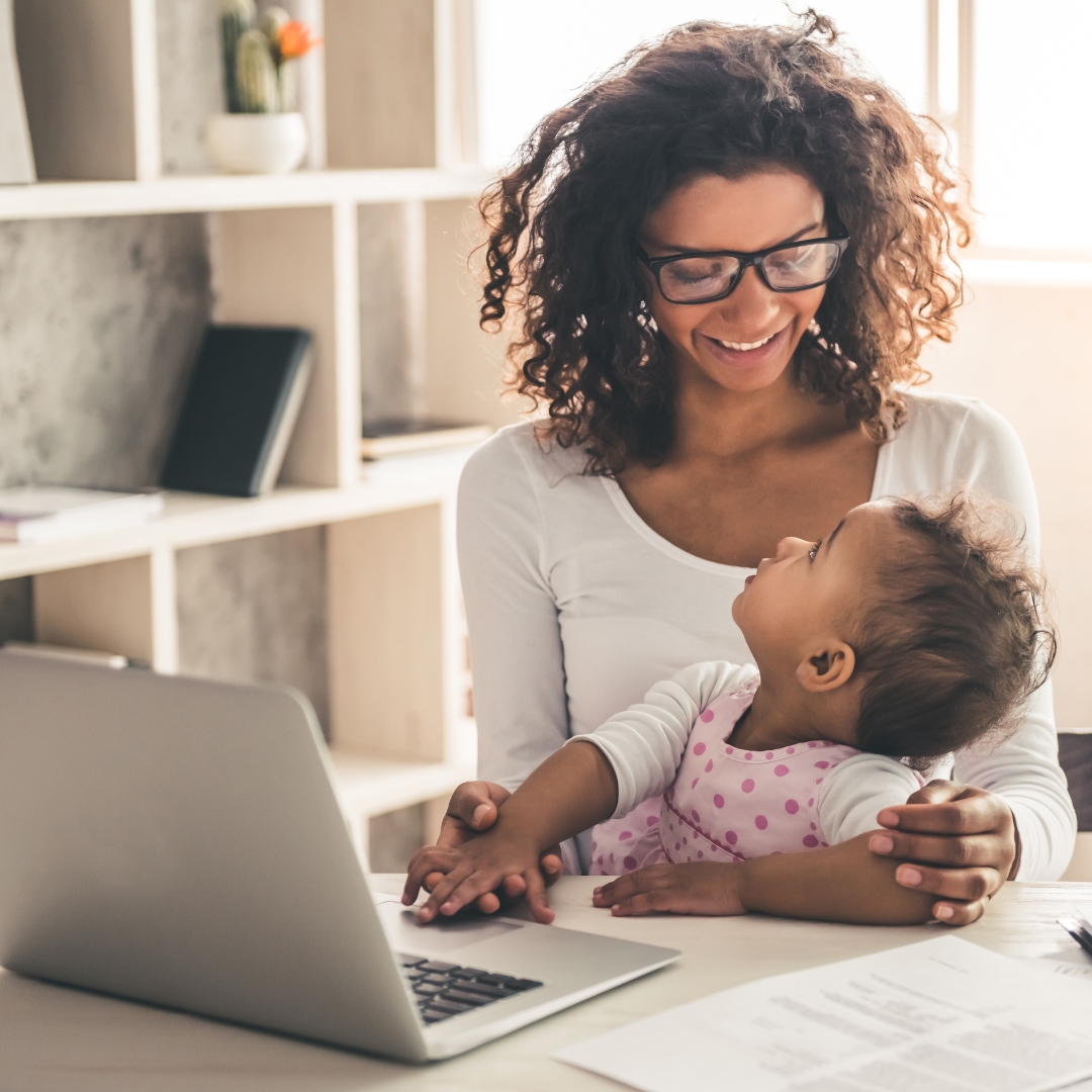 working mom on laptop holding baby