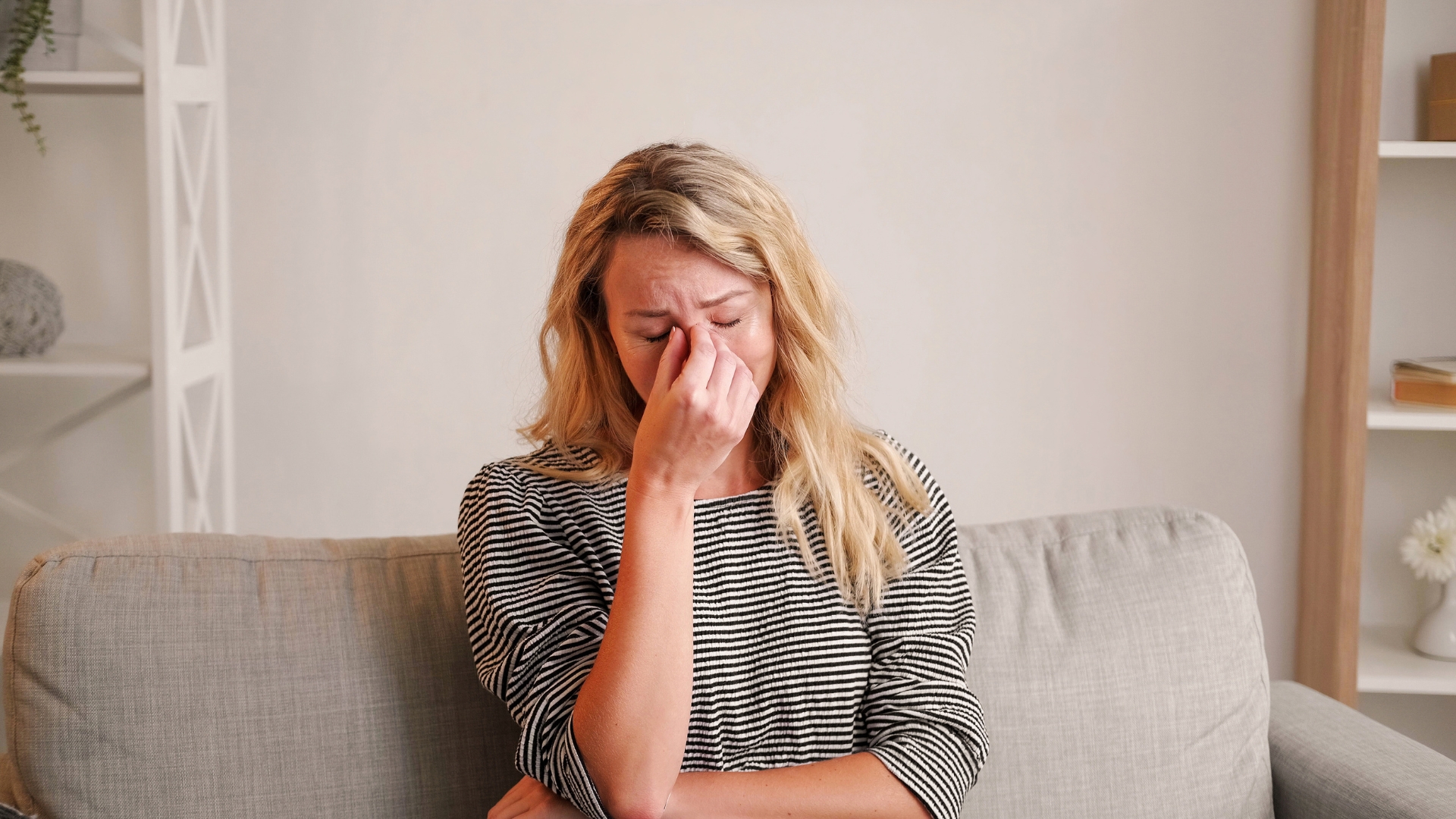 new mom experiencing postpartum depression symptoms sitting on the couch crying