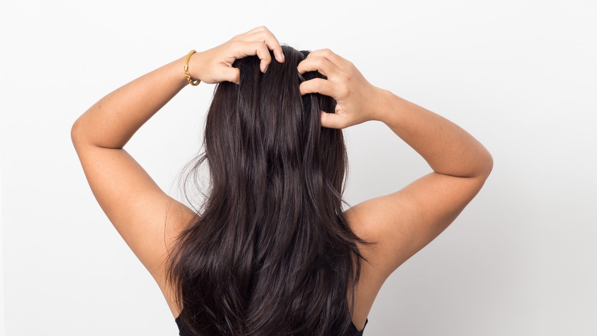 back of woman's head running fingers through her postpartum hair loss