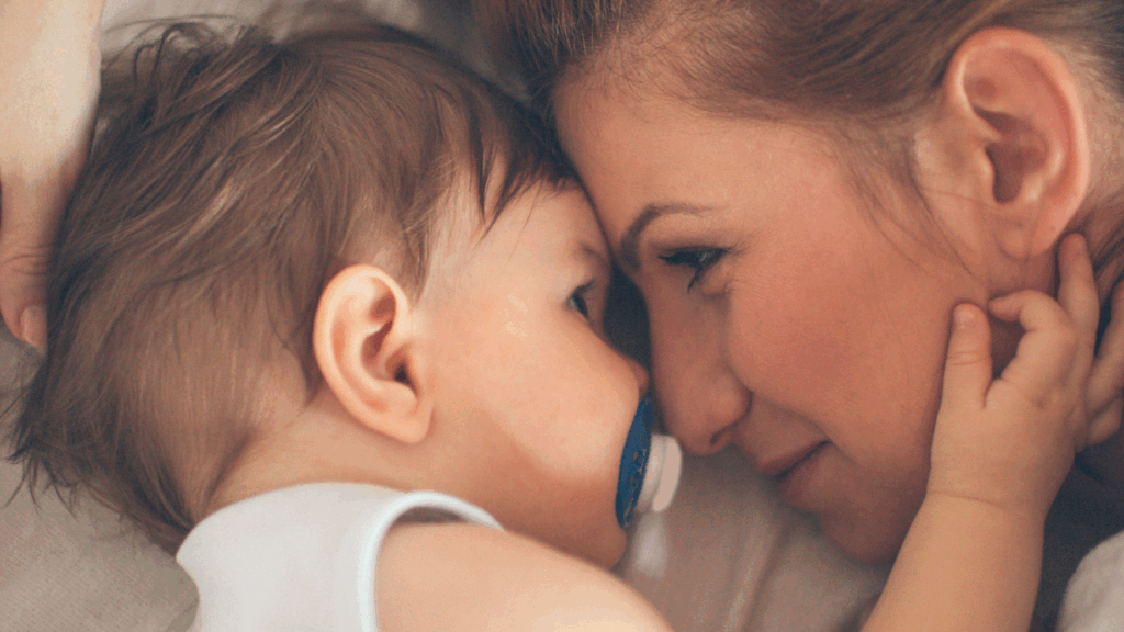 mother feeling both joy and stress as she handles the duality of motherhood looking at her young baby